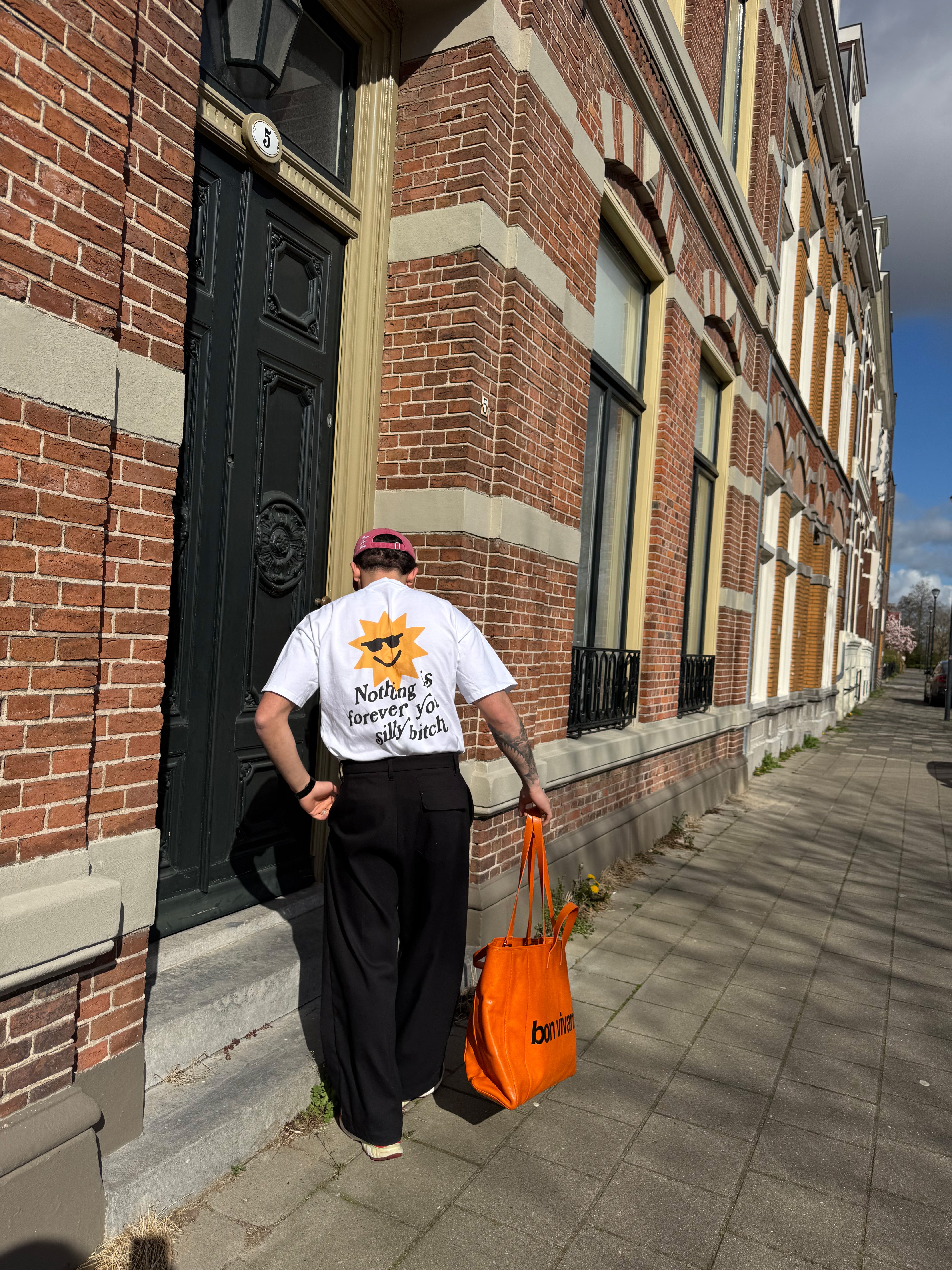 Model_Walking_And_Wearing_Boxy_Graphic_T-shirt_Nothing_Is_Forever_With_Orange_Bag