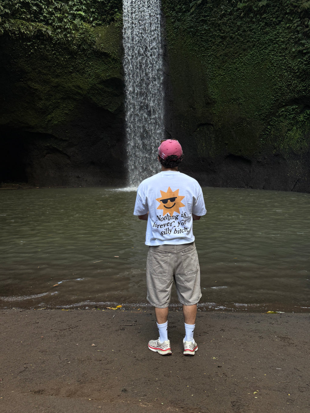 Person standing on a beach with a tree and water in the background